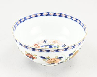une image représentant un bol posé sur une surface blanche, orné de fleurs bleues et orange