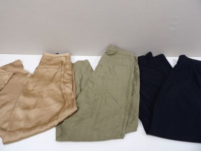 trois paires de pantalons sont alignées sur une surface blanche
