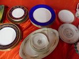 many plates and bowls on a table with a red table cloth