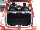 the back of a red car with its trunk open and the seats folded down