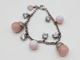 un gros plan d'un bracelet orné de perles roses et de breloques