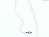 a close up of a necklace on a white surface with a chain