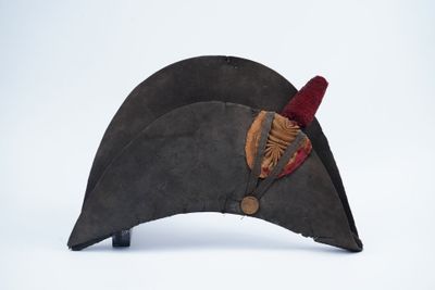 un vieux chapeau orné d'une plume, posé sur une surface blanche