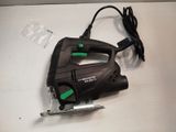 a black and green corded jig saw on a white table