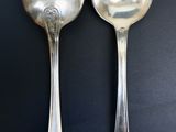 two silver spoons sitting next to each other on a table