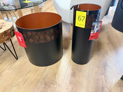 deux poubelles noires posées sur un parquet, à côté d'une table en verre