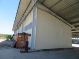 a white building with a metal roof next to a dumpster in the middle of a parking lot