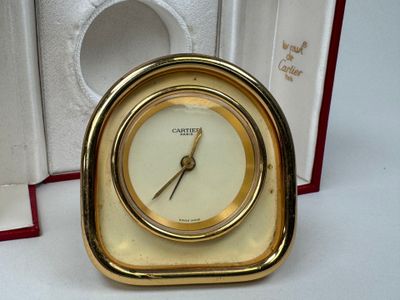 une horloge dorée avec un cadran blanc, dans un coffret