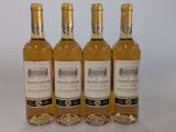 quatre bouteilles de vin sont alignées sur une surface blanche