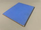un cahier bleu posé sur une table blanche