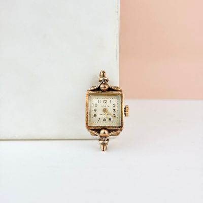 une petite montre en or posée sur une table blanche