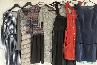 des vêtements suspendus à un portant dans une pièce où se trouvent des vêtements sur des cintres
