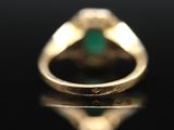 a close up of a gold ring with a green stone