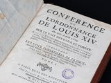 un livre ouvert, sur lequel est apposé un tampon, posé sur une table