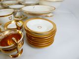 beaucoup d'assiettes et de tasses dorées et blanches sur la table