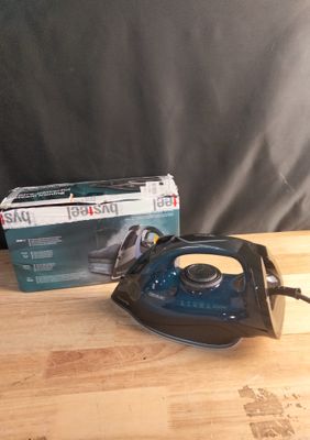 un fer à repasser noir et bleu posé sur une table à côté d'une boîte