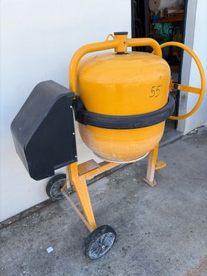 une bétonnière jaune posée sur un chariot à l'extérieur d'un bâtiment