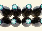 six bottles of wine are lined up in a row on a white surface
