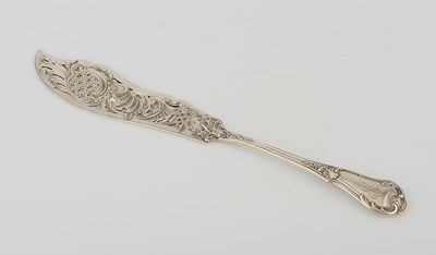 a silver spoon with ornate design on it sitting on a white surface