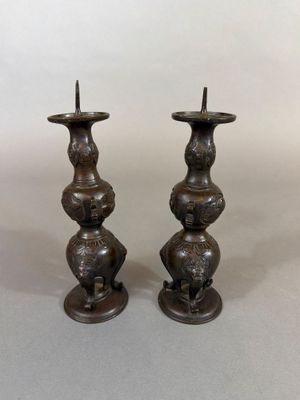 une paire de bougeoirs anciens en bronze sur socles, sur fond blanc