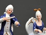 two figurines of a woman and a man sitting on a chair