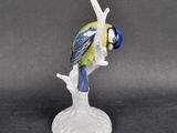 a figurine of a blue and yellow bird on a branch