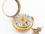 a small gold pocket watch with a key in it