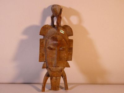 une image représentant une sculpture en bois d'un homme avec un oiseau sur la tête