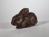 a brown rabbit statue sitting on top of a white surface