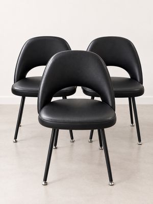 trois chaises noires aux pieds noirs, avec un mur blanc en arrière-plan
