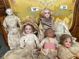several antique dolls are sitting on a chair in a room