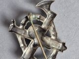 a silver brooch with a bird and a cross on it