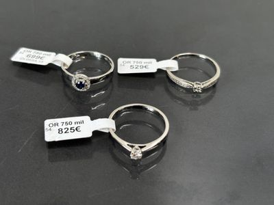 trois bagues avec leurs étiquettes de prix, posées sur une table
