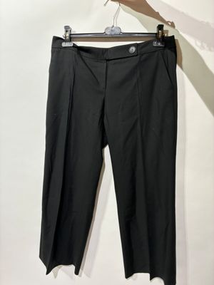 un pantalon noir suspendu à un cintre devant un mur blanc