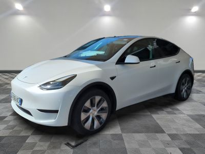 La Tesla Model Y blanche est garée dans une pièce dont le sol est à carreaux.