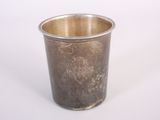 une tasse en argent posée sur une surface blanche
