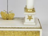 a white and gold clock on a stand with a butterfly on it