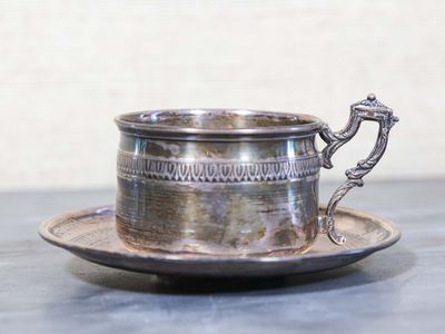 une tasse et une soucoupe en argent posées sur une table