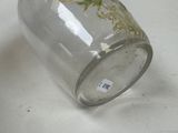 a glass jar with a flower on it sitting on a table