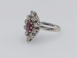 a close up of a ring with a ruby stone surrounded by diamonds
