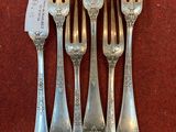 four forks and a knife are sitting on a red surface