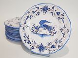 several blue and white plates with a bird on them on a table