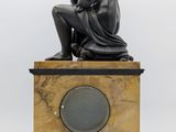 an image of a statue of a man sitting on top of a clock