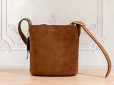 un sac à bandoulière en daim marron posé sur une table en bois