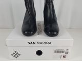 a pair of black leather ankle boots sitting on top of a white box