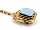 necklace with a blue stone on a gold chain on a white background