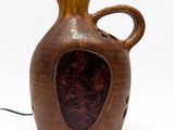 un vase brun posé sur une surface blanche