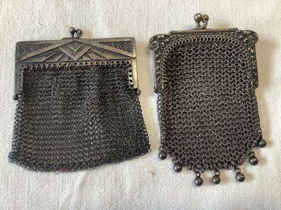 paire de petits sacs à main anciens en maille métallique argentée, posés sur un tissu blanc