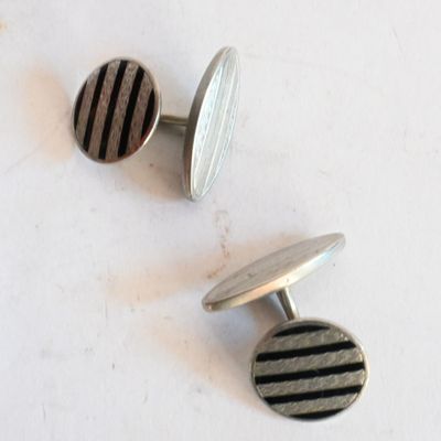 une paire de boutons de manchette rayés argent et noir sur un fond blanc