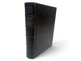 un vieux livre noir posé sur une surface blanche